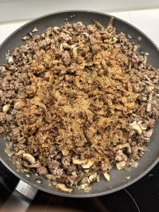 adding spices to sauteed beef, with onions, garlic and mushrooms
