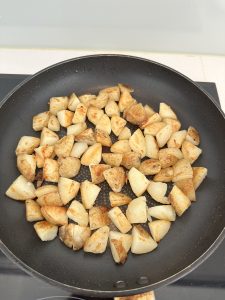 Golden boiled potatoes crisping in a non-stick pan for Spanish tortilla